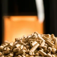 Kozę można palić pelletem. Widać stos pelletu na tle płonącego ognia w kominku.