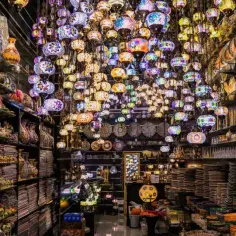 Sklep pełen kolorowych lamp i pamiątek z Dubaju. Wśród nich ozdobne wazony, złote figurki i bogato zdobione naczynia.
