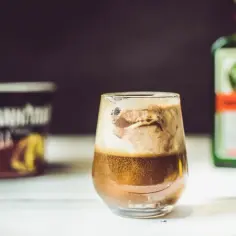 Pyszne drinki z jagera z lodami waniliowymi i pianką. Obok butelka Jägermeistera i puszka lodów.