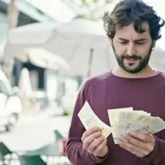 Mężczyzna liczy banknoty, zastanawiając się nad cenami w Kopenhadze.