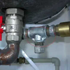 Metalowe złącze hydrauliczne z zaworem i czerwonym pokrętłem, z zaznaczonym obszarem.