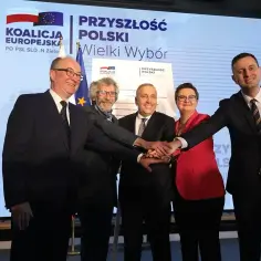 Pięcioro polityków zjednoczonych w koalicji, dłonie złożone na znak porozumienia.