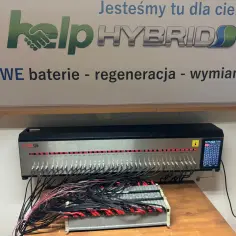 Profesjonalny balanser do baterii hybrydowych, podłączony do wielu ogniw. Urządzenie z wyświetlaczem pokazuje stan naładowania poszczególnych komórek.