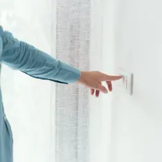 Osoba w niebieskiej koszuli naciska włącznik światła. Dowiedz się, jak podłączyć włącznik światła pojedynczy.