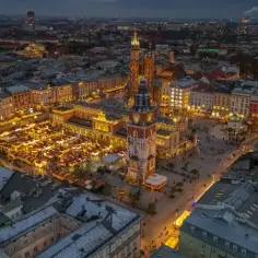 Nocny widok na jarmark bożonarodzeniowy krakow. Tłumy ludzi spacerują wśród rozświetlonych straganów na Rynku Głównym.