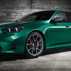 Nowa, zielona BMW M5 prezentuje się imponująco na tle betonowej ściany.