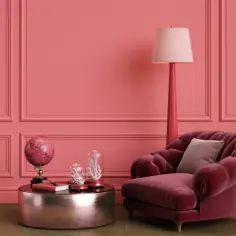 Elegancki salon w odcieniach różu z tapicerowanym fotelem, stolikiem z globusem i lampą. Listwy przypodłogowe w kolorze ścian tworzą spójną całość.