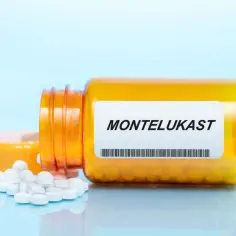 Pomarańczowa buteleczka leku Montelukast z rozsypanymi tabletkami.