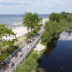 Rowerzyści przemierzają malowniczą trasę Velo Baltica wzdłuż plaży i spokojnej wody.