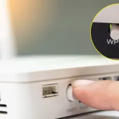 Palec naciska przycisk WPS na routerze, ułatwiając połączenie z siecią Wi-Fi.