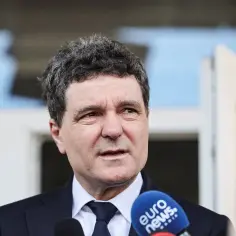 Prezydent Rumunii w garniturze odpowiada na pytania dziennikarzy, mikrofon Euro News w kadrze.