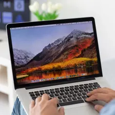 Osoba pisze na laptopie z piękną tapetą górską. Chcesz wiedzieć, jak zrobić print screen na Macu?
