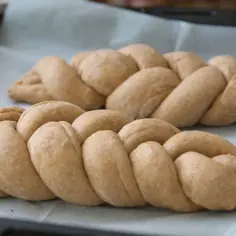 Dwie plecione chałki na papierze do pieczenia. Zastanawiasz się nad chałka kcal?
