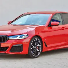 Czerwone BMW M550i z czarnymi felgami i sportowym pakietem.