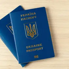 Dwa niebieskie paszporty Ukrainy leżą na drewnianym tle. Czy do Ukrainy potrzebny jest paszport? Tak, do podróży zagranicznych.