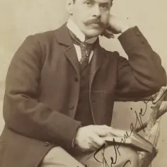 Portret mężczyzny z wąsami, w eleganckim stroju, z ręką opartą o głowę. Widoczny podpis "Tetmajer".