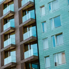 Nowoczesne balkony z przeszklonymi balustradami i okna w turkusowej elewacji. Marzenie o własnym mieszkaniu z dofinansowaniem do mieszkania staje się realne.