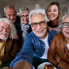 Uśmiechnięci seniorzy robią sobie selfie. Zastanawiają się, ile lat jest ochrony przedemerytalnej, by móc cieszyć się życiem.