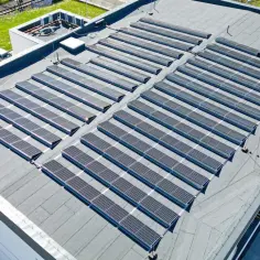 Panelami fotowoltaicznymi pokryty jest dach płaski budynku. To nowoczesne rozwiązanie dla pozyskiwania energii.
