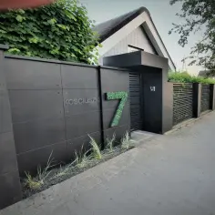 Nowoczesne ogrodzenie z betonu architektonicznego, z numerem posesji 7 i nazwą ulicy.