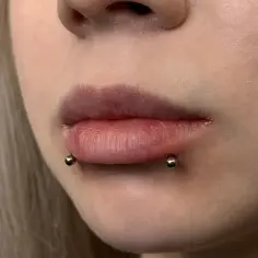 Usta z piercingiem snake bite, podkreślającym ich kształt.