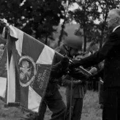 Uroczystość przekazania sztandaru. Na fladze widnieje napis "Bóg, Honor, Ojczyzna" i godło Polski.