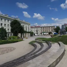 Słoneczny dzień na placu artystów w Kielcach. Nowoczesna architektura, zielone skwery i ławki tworzą przyjazną przestrzeń.