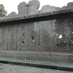 Pomnik ofiar Powstania Warszawskiego, zniszczony i naznaczony kulami, przypomina o tragedii. Ocalony Tadeusz Różewicz w swojej interpretacji ukazuje okrucieństwo wojny.
