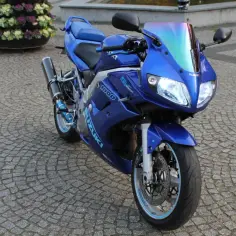 Błękitny Suzuki SV1000, sportowy motocykl, lśni na brukowanej nawierzchni.