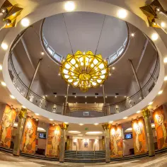 Eleganckie wnętrze teatru muzycznego, gdzie kasa biletowa jest tuż obok imponującej klatki schodowej i ozdobnych mozaik.