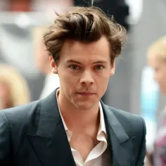 Harry Styles w garniturze, z burzą włosów. Czy Harry Styles jest gejem? Pytanie, które nurtuje fanów.