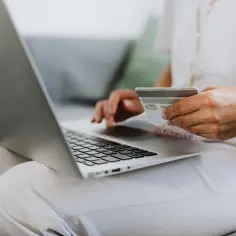 Personne utilisant un ordinateur portable et une carte bancaire.