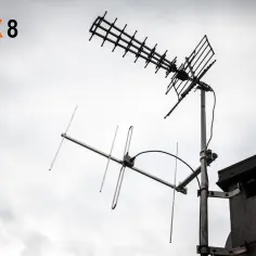 Dwie anteny telewizyjne na tle pochmurnego nieba.