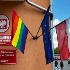 Tęcza lgbt powiewa obok flag Polski i UE przed szkołą w Koninie.