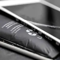 Widoczny spuchnięty akumulator iPhone, który wypycha ekran. To niebezpieczne zjawisko, które wymaga natychmiastowej wymiany.