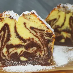 Wilgotna babka marmurkowa na oleju, oprószona cukrem pudrem, kusi apetycznym wyglądem.