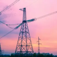 Wieże energetyczne na tle różowego nieba. Linie wysokiego napięcia tworzą skomplikowany wzór, jakby odzwierciedlając wzór na częstotliwość.
