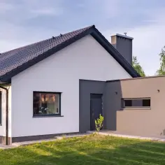 Nowoczesny dom z białym i grafitowym tynkiem. Elewacja domu prezentuje się elegancko, podkreślając jego architekturę.