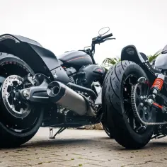 Dwa motocykle z dwoma kołami z przodu, jeden czarny Harley-Davidson, drugi z pomarańczowymi akcentami.
