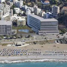 Widok z lotu ptaka na nowoczesny Rhodos Horizon Resort z basenem i plażą pełną leżaków.