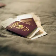Kilka paszportów i biletów leży na szarym materiale. Czy na zdjeciu do paszportu moga byc kolczyki?