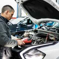 Mechanik sprawdza auto, by dowiedzieć się, ile kosztuje przegląd samochodu.