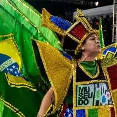 Tancerka w barwnym stroju z flagą Brazylii na tle tłumu podczas karnawału w Rio.