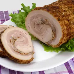 Rolowany boczek z przyprawami, pokrojony w plastry, podany na sałacie. Sprawdzony przepis na boczek rolowany, który zachwyci każdego.