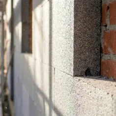 Ściana z bloczków styropianowych i cegły, w tle rusztowania budowlane. Projekt wt2021 w toku.