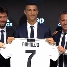 Cristiano Ronaldo z koszulką Juventusu z numerem 7, trzymaną przez niego i dwóch mężczyzn w garniturach.