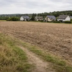 Pola uprawne obok domów. Widać ślady przekształcenia działki rolnej na budowlaną, przygotowywane pod nowe inwestycje.