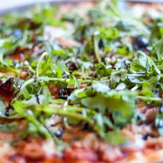 Chrupiąca pizza z tuńczykiem, rukolą i oliwkami, polana sosem balsamicznym.