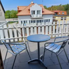 Willa Patryk Jastrzębia Góra: balkon z metalowym stolikiem i dwoma krzesłami, widok na inne budynki i zieleń.