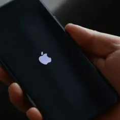 Dłoń trzyma iPhone'a z logo Apple. Dowiedz się, jak wyłączyć iPhone bez dotyku.